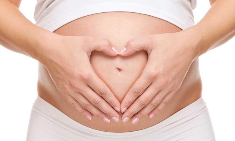 A woman holds her pregnant belly after optimizing her chance of pregnancy with IVF